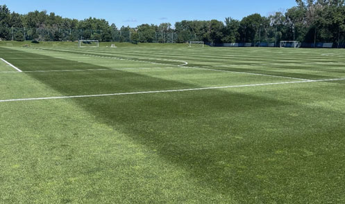 View of an outdoor sports field with artificial grass.
